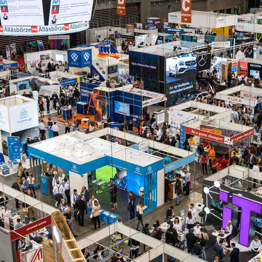 Photobooth huren voor beurs of zakelijk event: overzicht van drukbezochte beursvloer met stands en bezoekers.